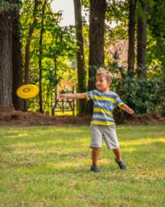 Little boy playing with yellow frisbee 
